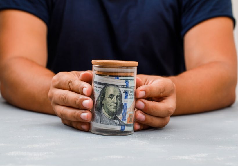 hombre mostrando dinero en un tarro
