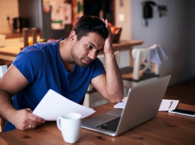 hombre preocupado viendo su laptop por las finanzas de su hogar